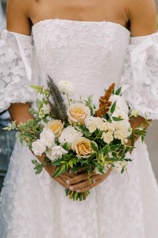 bride holding white, green, caramel coloured bouquet